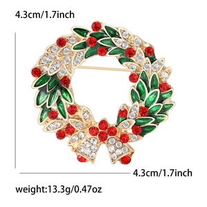 Christmas wreath brooch with red rhinestones and green leaves on a white background