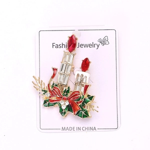 Détail d'une broche bougie de Noël avec nœud en émail rouge et strass étincelants