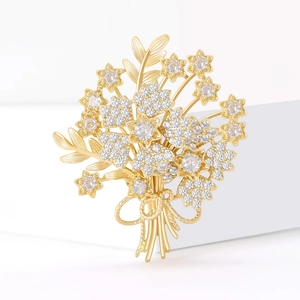 Elegant gold bouquet brooch with cubic zirconia crystals on a modern white background