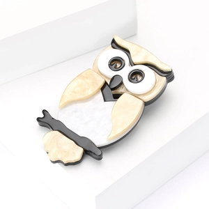 Broche hibou chic en acrylique avec texture marbrée sur fond blanc minimaliste