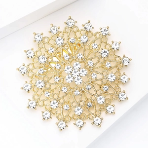 Detailaufnahme der goldenen Mandala-Brosche mit funkelnden Strasssteinen auf weißem Sockel