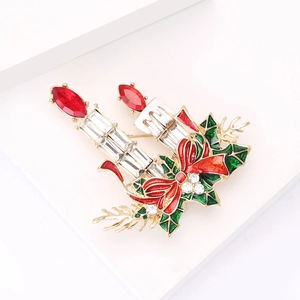 Broche bougie de Noël avec strass rouges et feuilles vertes sur un fond blanc pur