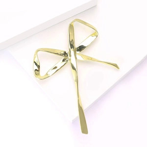 Vue détaillée de l'élégante broche nœud dorée avec finition miroir polie et lignes fluides