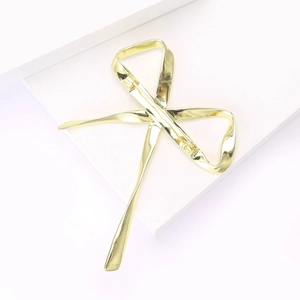 Détail d'une élégante broche nœud dorée polie avec finition métallique lisse et épingle
