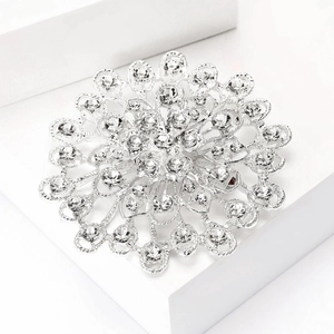 Détail macro d'une broche tournesol argentée sertie de strass brillants sur support