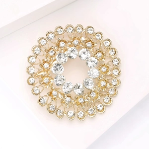 Macro detail of luxury gold-tone round brooch featuring sparkling white rhinestones