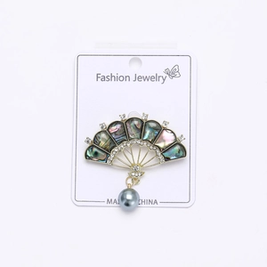 Detail of fan-shaped brooch featuring iridescent abalone shell, rhinestones and grey pearl