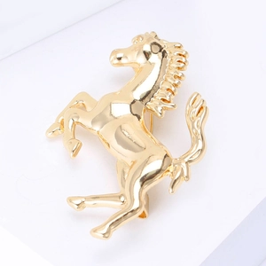 Spilla a forma di cavallo rampante in metallo dorato lucido su sfondo bianco