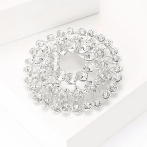 Detailed macro of silver rhinestone circular brooch with intricate cutout floral textures