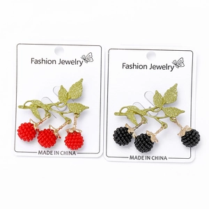 Detailed close-up of enamel raspberry and blackberry brooches on display cards