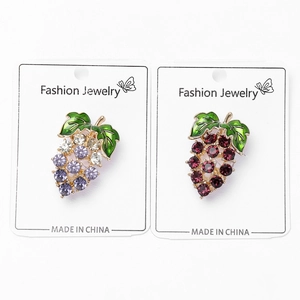 Close-up of sparkling grape crystal brooches in purple and red with green enamel leaves