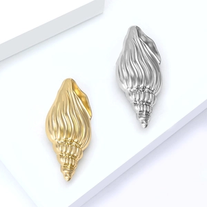 Polished shell-shaped brooches in gold and silver finish on a white geometric stand
