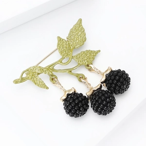 Detailed macro view of enamel blackberry brooch with green leaves and golden metal stem