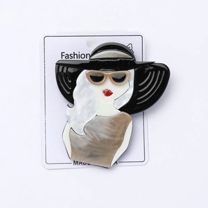 Vue détaillée d'une broche en acrylique représentant une femme avec un chapeau noir sur carte