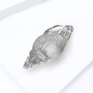 Silver conch shell brooch back view showing secure horizontal pin fastener and metal texture