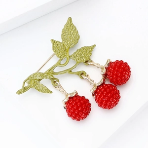 Macro detail of enamel blackberry brooch with three red berries and green leaves