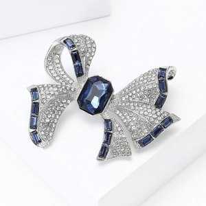 Detailed close-up of bow brooch with silver base, clear rhinestones and blue crystals