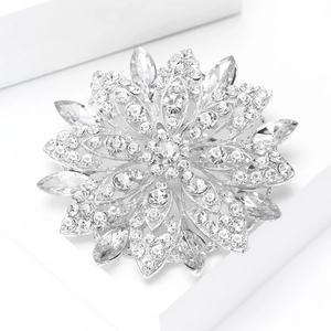 Dettaglio macro di una spilla a fiore argentata con strass scintillanti su supporto bianco