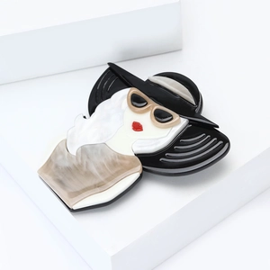Détail d'une broche en acrylique rétro pour femme avec chapeau noir et lèvres rouges