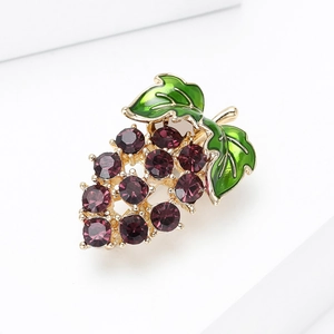 Detail view of grape brooch with purple crystals and green enamel on a gold base