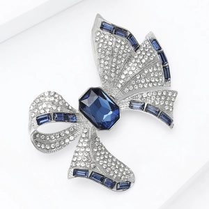 Close-up of luxury bow brooch featuring navy blue rectangle stone and sparkling crystal inlay