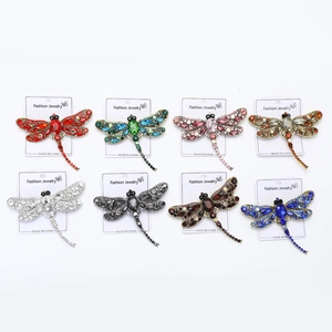 Macro shot of eight colorful rhinestone dragonfly brooches on white display cards