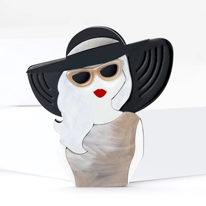 Vue détaillée d'une broche en acrylique représentant une femme au chapeau noir et lèvres rouges