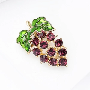 Macro shot of sparkling purple crystal grapes and green leaf detail on a gold-tone brooch