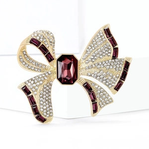 Luxurious gold bow brooch featuring a purple center stone and crystal-encrusted wings