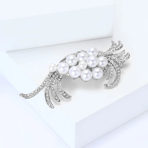 Detailed close-up of a silver-tone brooch featuring radiating lines with pearls and rhinestones