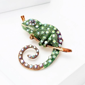 Détail macro de la broche caméléon en émail avec strass colorés et branche dorée