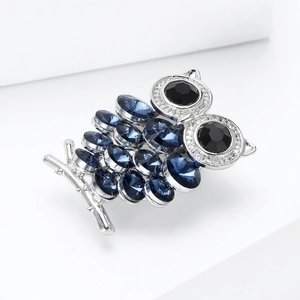 Detail van uilenbroche met diepblauwe kristallen en zwarte edelsteenogen op zilver metaal
