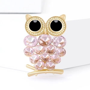 Prachtige gouden uil broche met roze kristallen en strassteentjes op witte sokkel