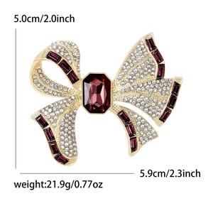 Luxury gold bow brooch with sparkling crystals and purple gemstones measuring 5.9cm wide