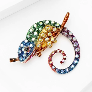 Vue macro d'une broche caméléon sertie de strass colorés sur une branche dorée