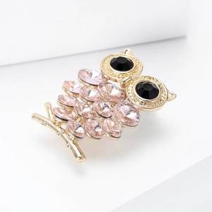 Close-up van uilbroche met roze kristallen en zwarte edelsteen ogen op gouden tak