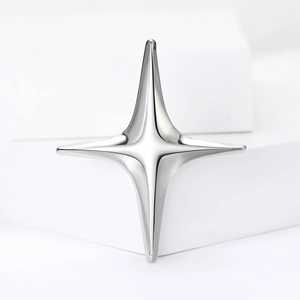 Polished silver four-pointed star brooch minimalist metal jewelry on white pedestal