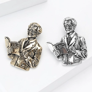Vintage gold and silver scholar brooches featuring a male teacher holding an ABC book