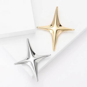 Polished gold and silver star brooches displayed on minimalist geometric pedestals