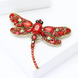 Close-up of vintage gold dragonfly brooch with red rhinestones and crystal details