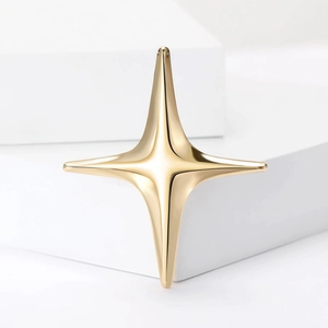 Macro detail of minimalist gold four-pointed star brooch on white geometric display stand