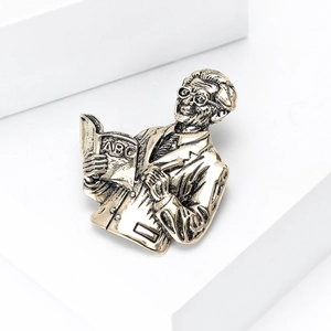 Detail of vintage gold professor brooch with ABC book on white geometric stand