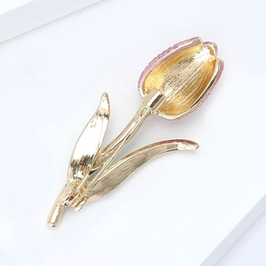 Detailed close-up of a golden tulip brooch featuring elegant pink enamel petals and texture