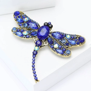Close-up detail of vintage dragonfly brooch with blue rhinestones on antique gold base