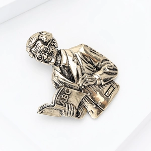 Macro shot of vintage scholar brooch in antique gold finish showing intricate embossed details