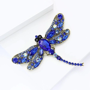 Detailed macro shot of dragonfly brooch with deep blue rhinestones on gold alloy base