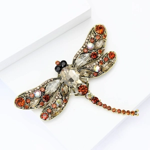 Detailed close-up of a dragonfly brooch with colorful rhinestones on a golden base