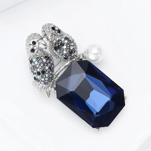 Close-up of luxury double bird brooch with blue rectangle crystal and white pearl