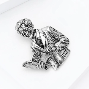 Macro shot of vintage silver-tone teacher brooch showing detailed engraving of elderly man