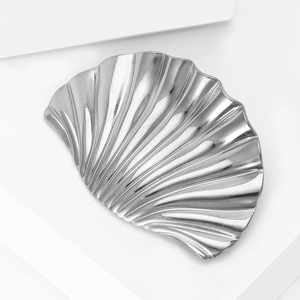 Macro detail of a shell-shaped silver metal jewelry tray with textured surface